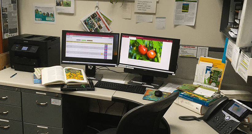 desk with printer, computer, open books, telephone