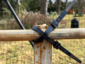zip ties holding a piece of conduit to a fence post