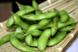 green edamame pods on a tan bamboo mat
